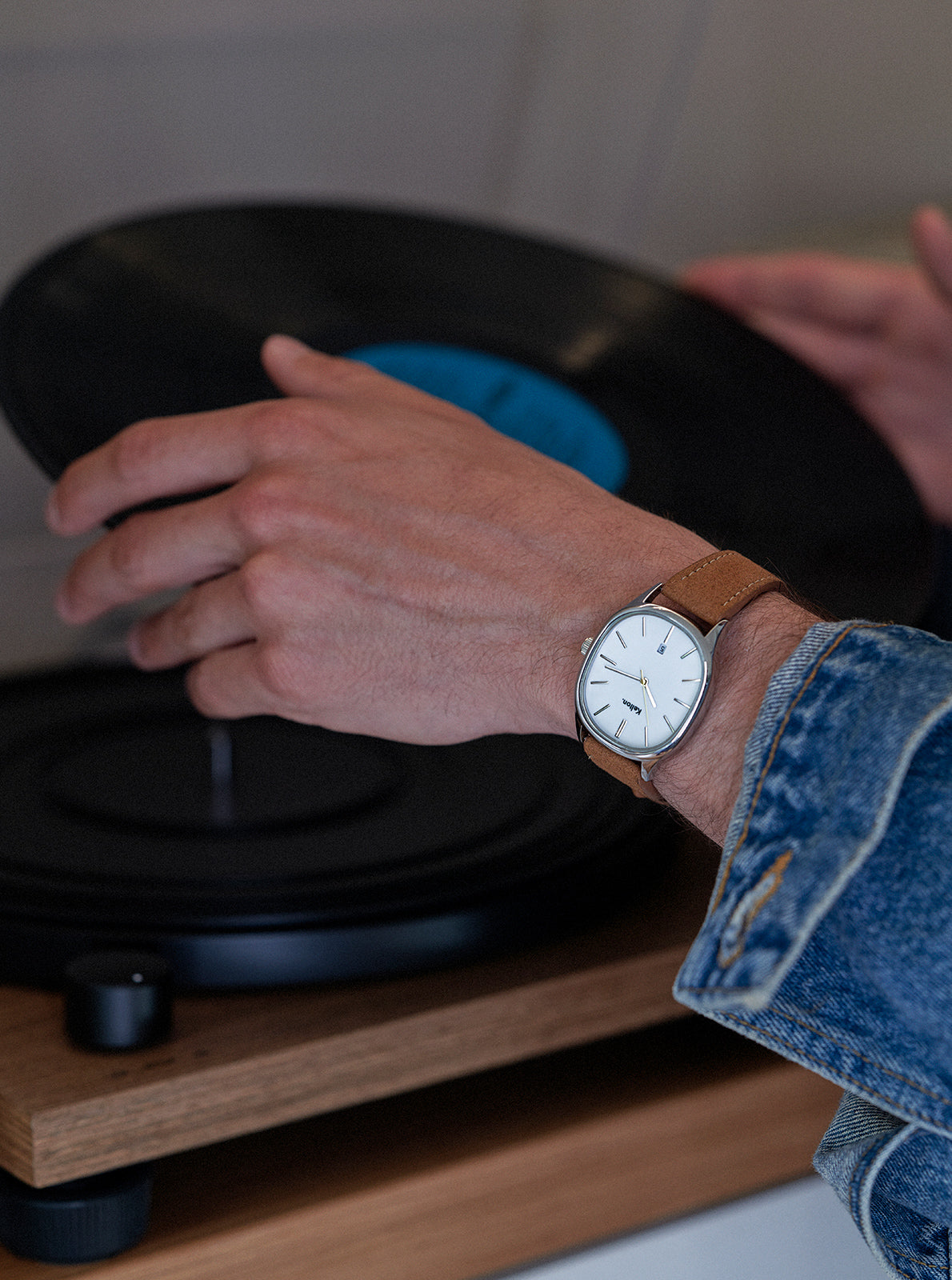 Image of Montre à cadran rond blanc, bracelet en cuir marron, fermoir visible, portée au poignet.