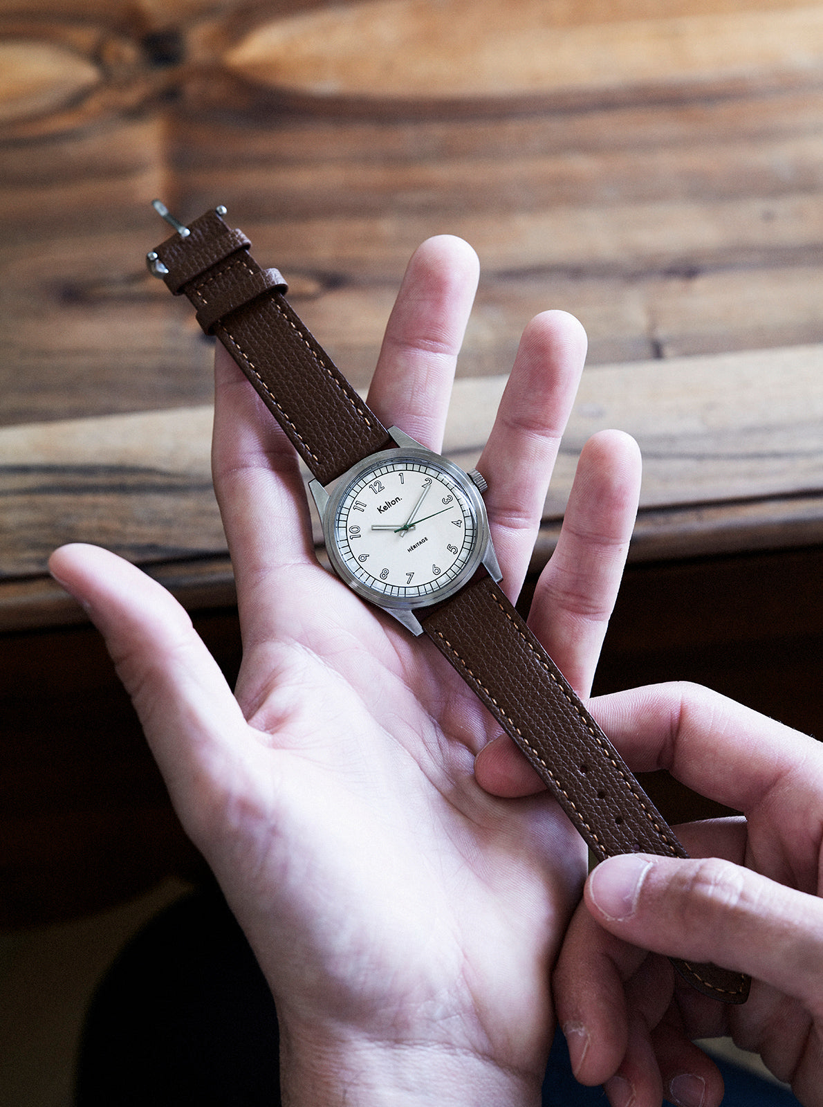 Image of Montre à cadran clair, bracelet cuir brun foncé, boîtier sombre, aiguilles visibles