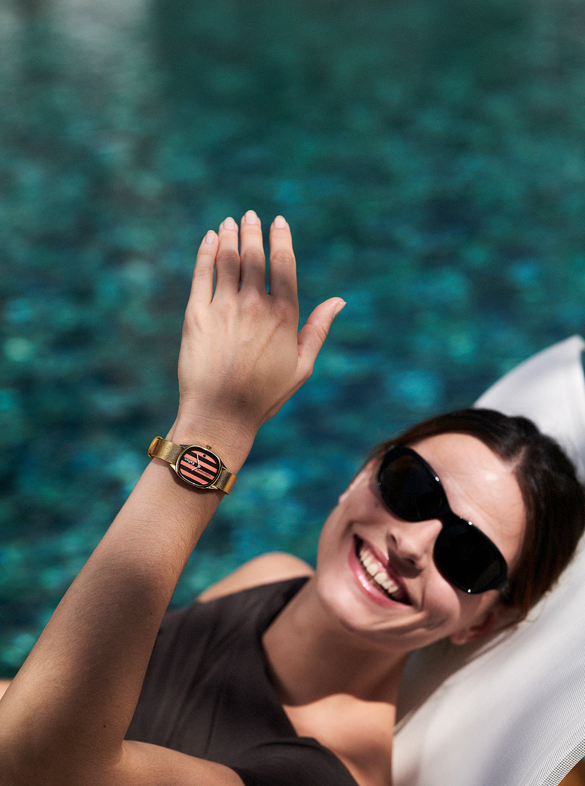 Image of Montre bracelet doré, cadran rond rayé pêche et rouge, poignet porté
