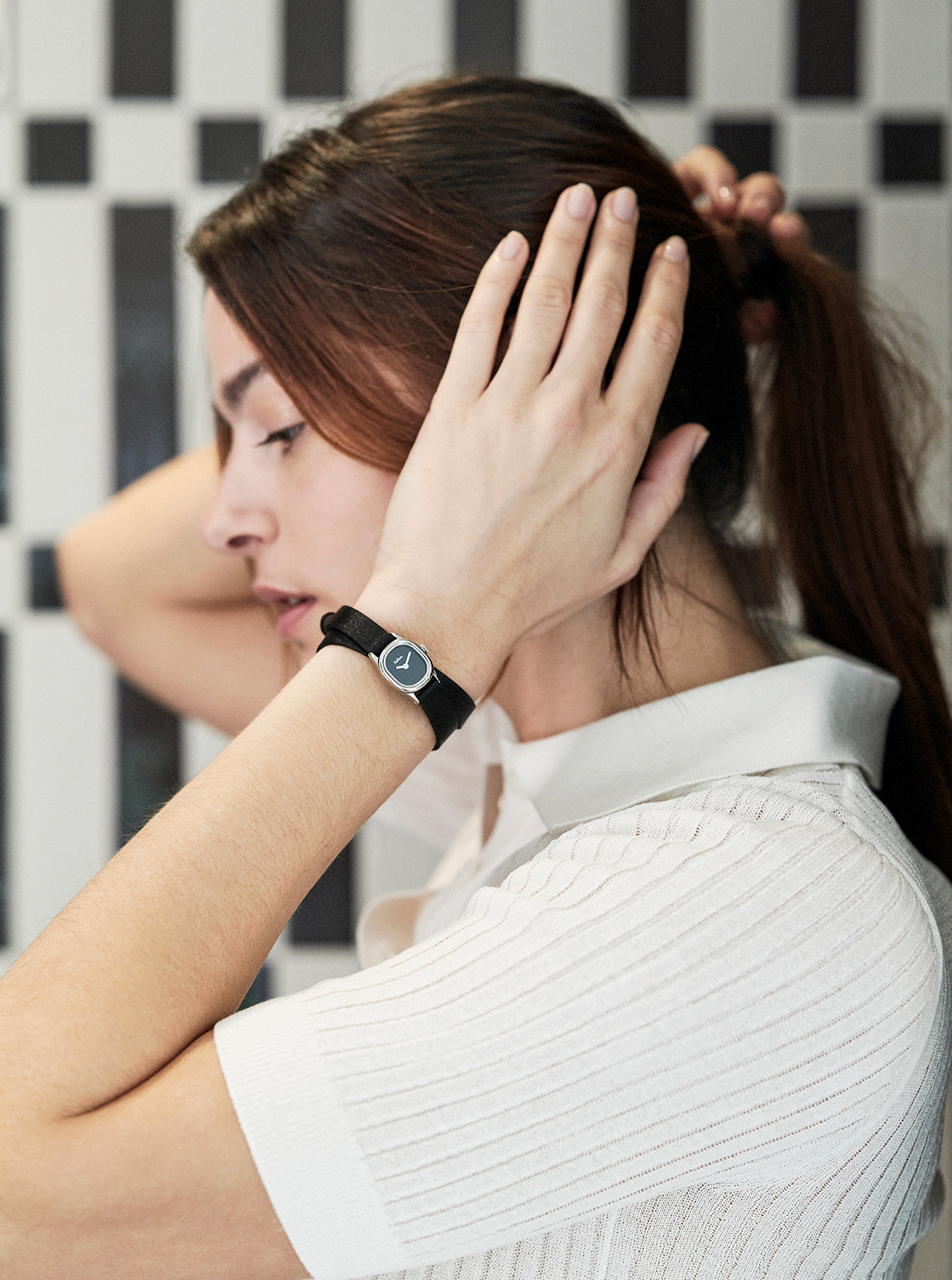 Image of Montre Minicolo noire au poignet, bracelet cuir noir et cadran rond