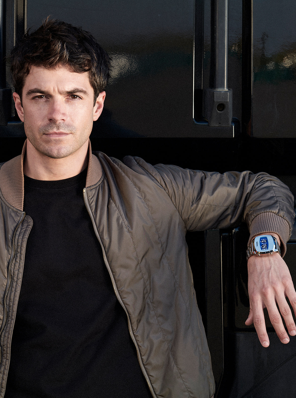 Image of Montre à écran bleu sur bracelet acier, portée avec veste brune