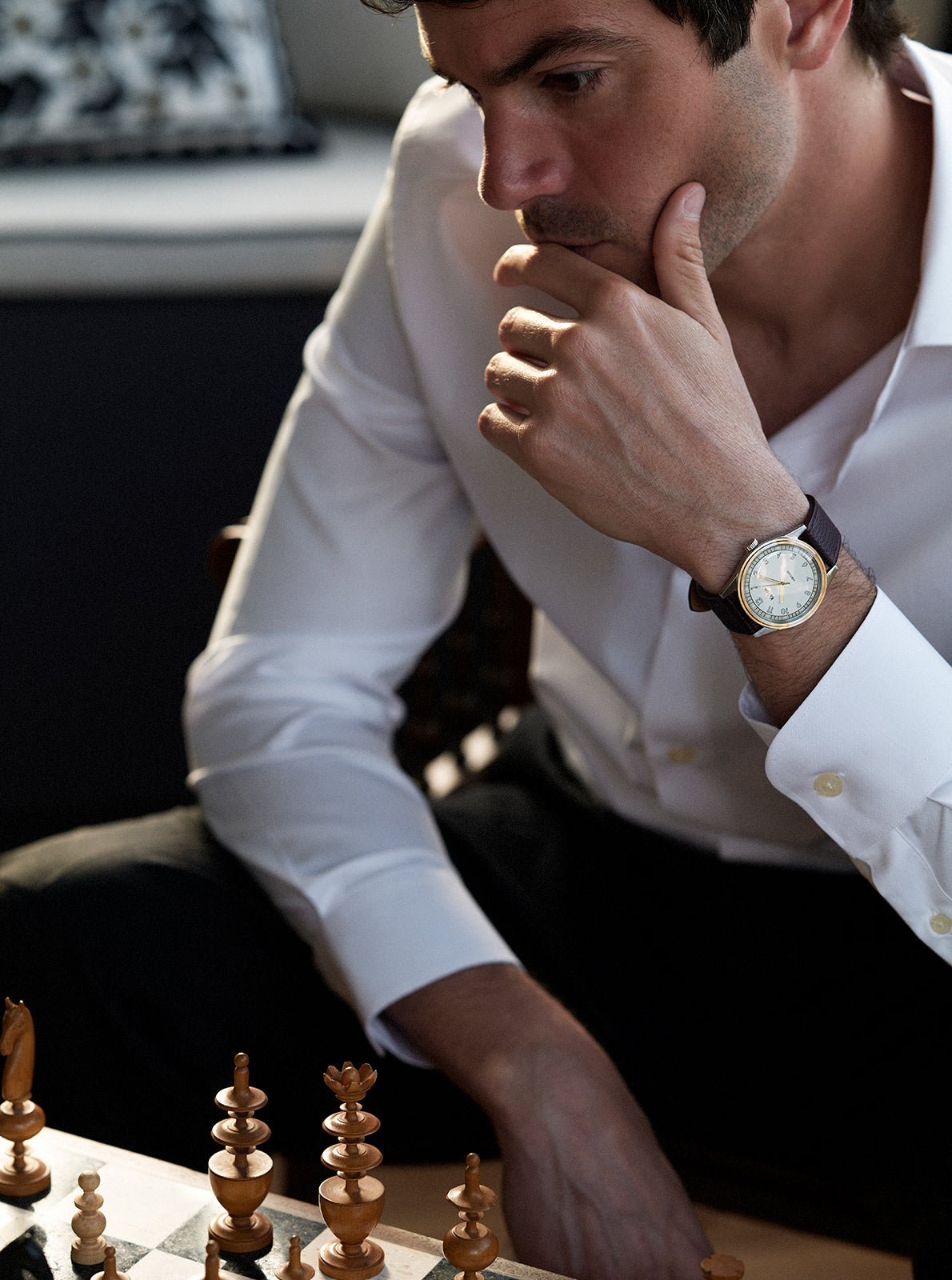 Image of Montre au poignet d’homme, cadran clair, bracelet cuir brun foncé, boîtier rond sombre