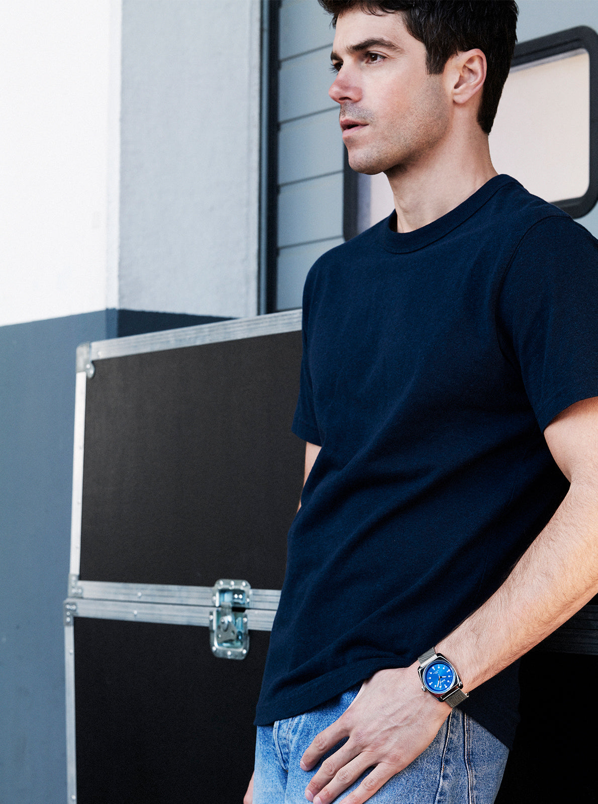 Image of Montre au poignet : cadran bleu, boîtier rond noir, bracelet maille.