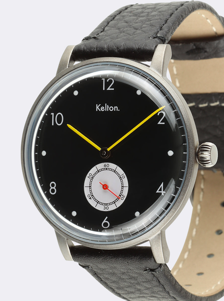 Image of Montre cadran noir, gros plan sur bracelet cuir noir et aiguilles jaunes.
