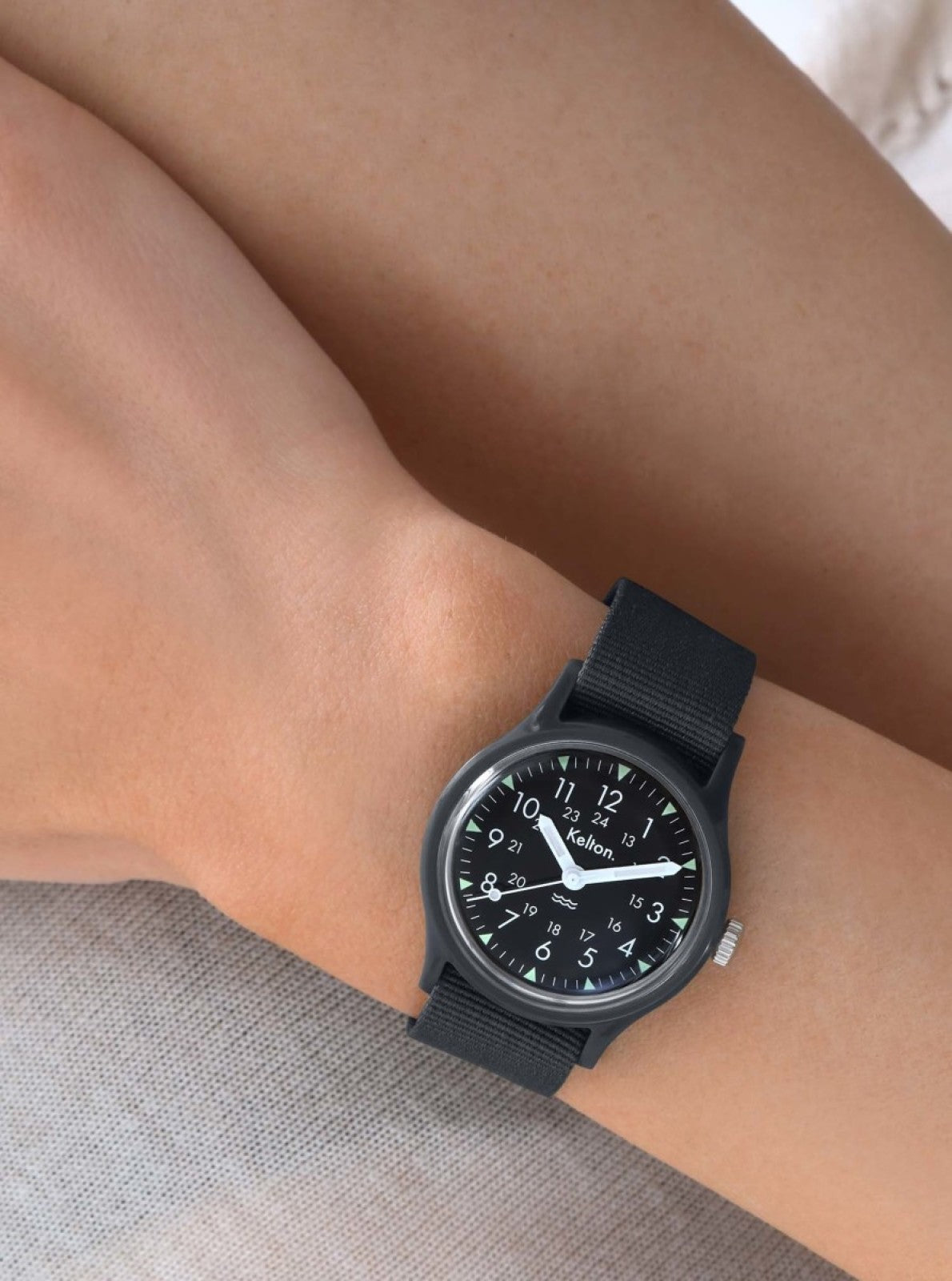 Image of Montre à quartz Kelton noire au poignet, bracelet tissé noir et cadran rond