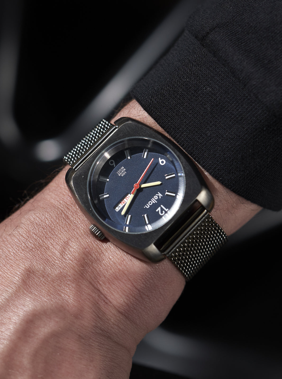 Image of Montre portée au poignet, cadran bleu marine et bracelet maille métallique sombre
