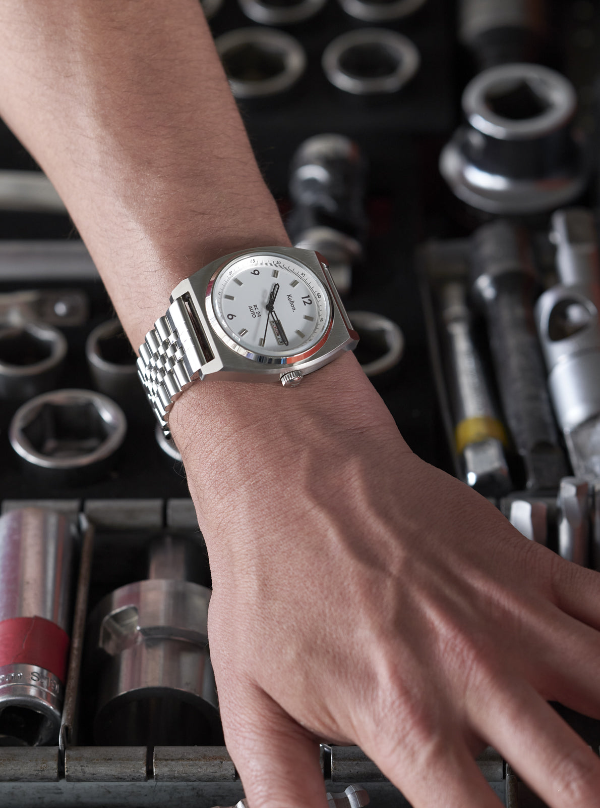 Image of Montre automatique au poignet, bracelet métal clair et cadran blanc avec guichet date