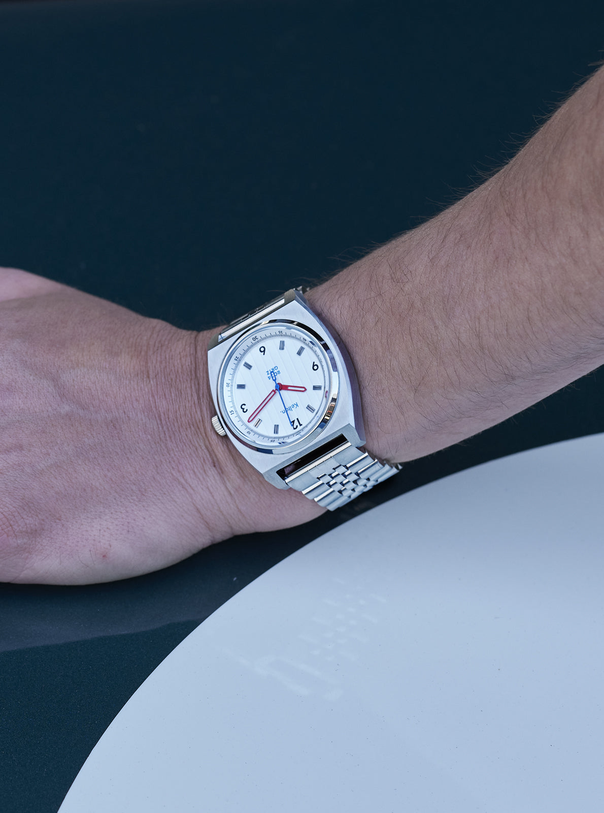 Image of Montre au poignet: cadran blanc, bracelet en acier, boîtier argenté.