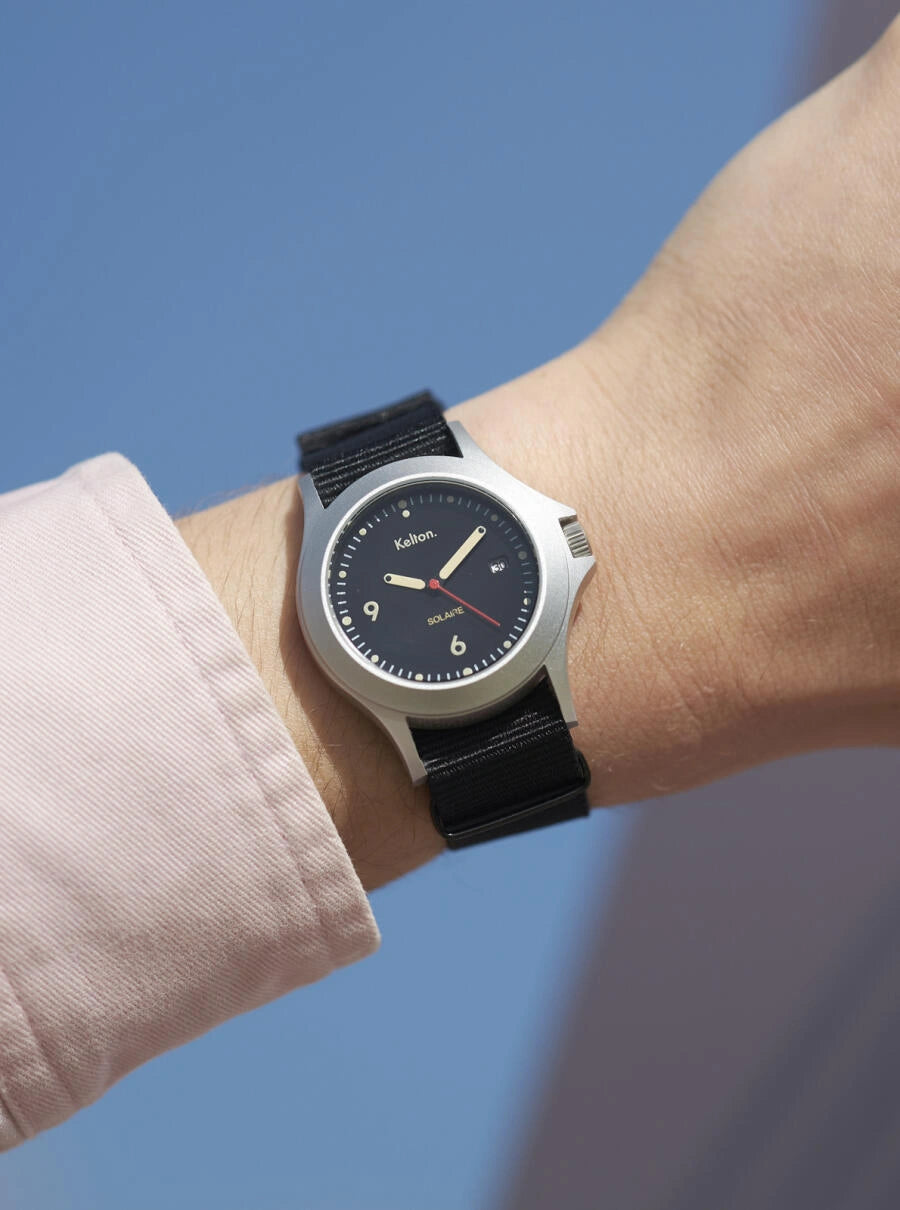 Image of Montre solaire à cadran noir, bracelet NATO noir, boîtier argenté, affichage analogique.