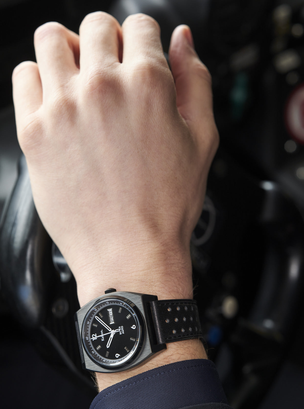 Image of Montre RC 24 noire au poignet, cadran noir et bracelet noir perforé.