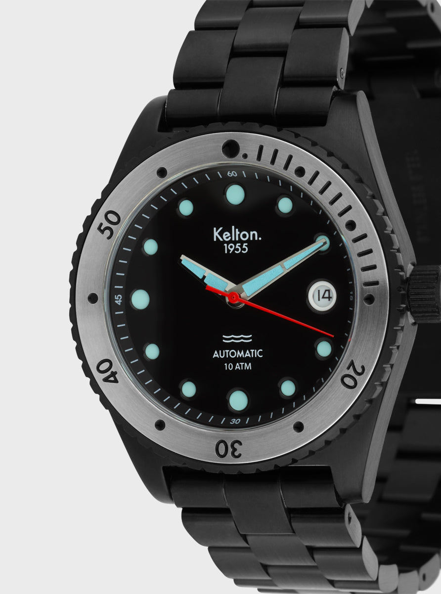 Image of Montre Kelton 1955 noire, gros plan du cadran noir avec index turquoise et aiguilles rouges