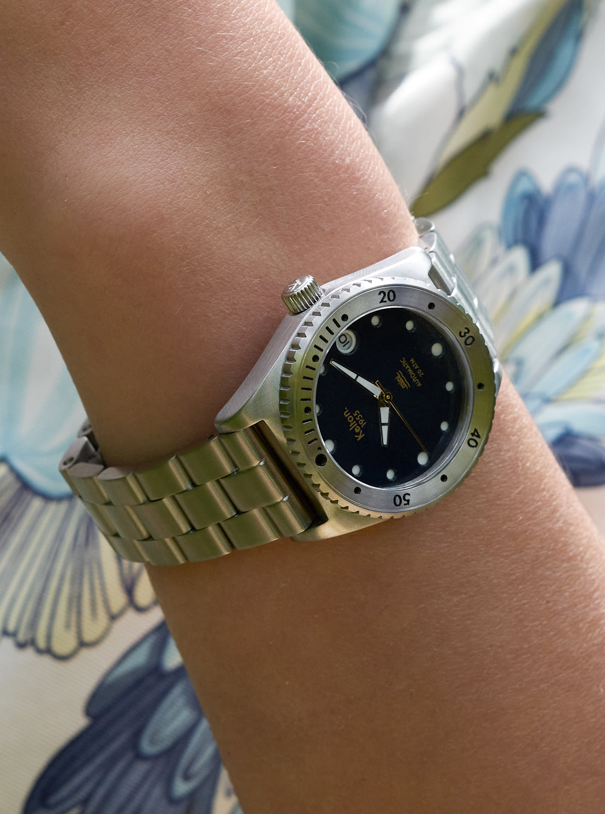 Image of Montre de plongée Mini portée : cadran bleu nuit, bracelet métallique à maillons.